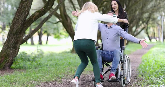 Young woman hugs happy man in a wheelchair on walk in park 4k movie