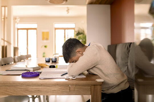 Tired boy with head down over table in living room