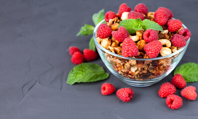 A bowl of granola with fresh raspberries on a dark background. Healthy food concept. ?lose-up. Place for text.