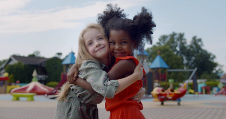 Diverse happy kids hugging on children playground - obrazy, fototapety, plakaty
