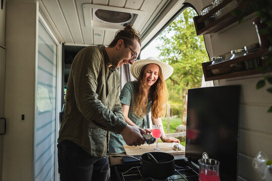 Happy couple preparing juice in camping van during vacation