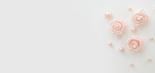Pink flowers and pearls on the white background, with free space for text, copy space. White roses. Minimalist design. Background for birthday, women's day, anniversary, wedding. Top view, flat lay.