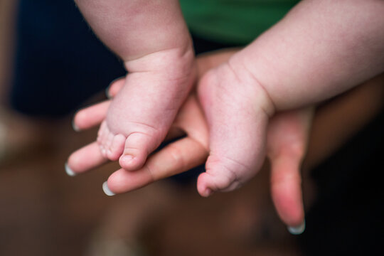 Image of little baby  legs in mother hands. Focus on baby fingers.