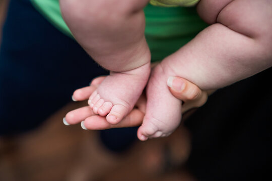 Image of little baby  legs in mother hands. Focus on baby fingers.