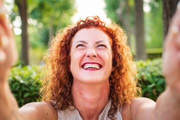 
Selfie portrait of mature business executive woman in her 50's smiling with curly red hair and...