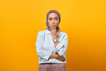 Portrait of scared Asian woman listening to bad news over yellow background