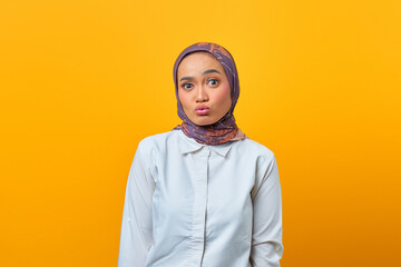 Portrait of beautiful Asian woman with shocked expression over yellow background