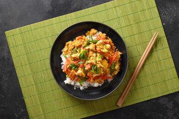 Thai breakfast Gai Pad Pongali with chicken, eggs, spicy, yellow thai curry paste,tomato, rice in black bowl made in wok. Close up. Pan-Asian cuisine. Thai Food Stir Fried.