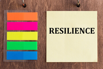 RESILIENCE on crumpled yellow paper on wooden background