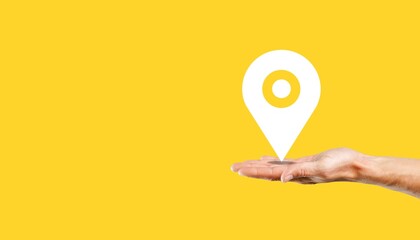 Big location symbol in hand over colored background