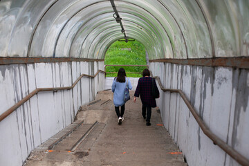 The women go down the stairs. People walk up the stairs.