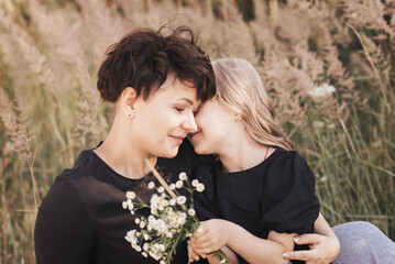 Mom gently hugs her daughter in nature in the summer, happy motherhood