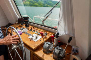 Mano de un hombre capitán de una embarcación dandole dirección en el agua del lago Arenal Costa Rica - obrazy, fototapety, plakaty
