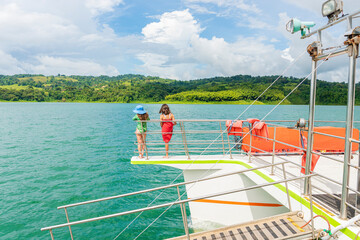 Niñas irreconocibles en un catamarán en el lago arenal en Costa Rica - obrazy, fototapety, plakaty