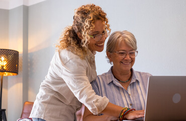 Beautiful blonde adult daughter teaching her mother how to use the network with digital laptop....