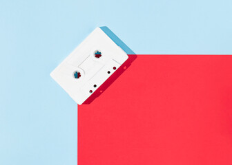 Retro white audio music cassette tape on a blue and red background. Minimal vintage concept. Flat lay with copy space. Bold colors.