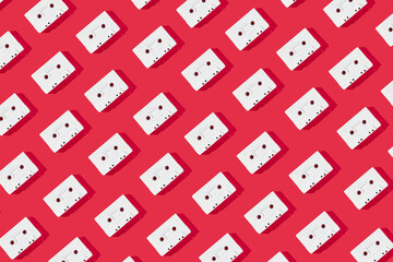 Pattern made of retro white audio music cassette tapes on a bold red background. Minimal vintage concept. Flat lay.