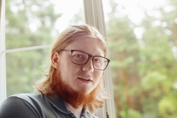 portrait of  young bearded man against  background of  window