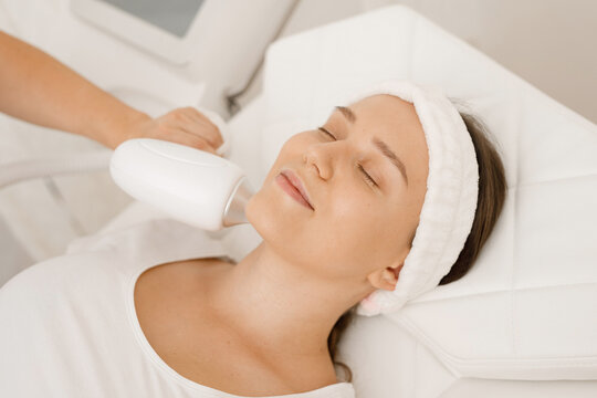 Young woman having laser hair removal procedure of face zone by specialist in cosmetic center. Removes pigmentation in cosmetic clinic. Intensive Pulsed Light Therapy. Anti-aging treatments.