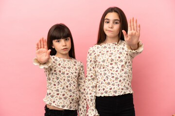Little sisters girls isolated on pink background making stop gesture denying a situation that...
