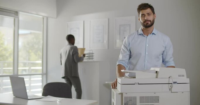 Portrait of successful businessman standing neat copier and smiling at camera