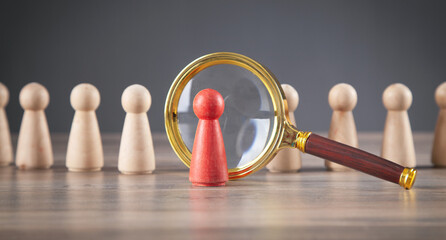 Magnifying glass and wooden human figures.