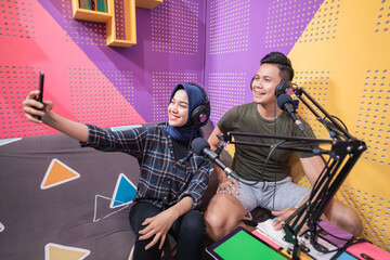 Fototapeta na wymiar couple in podcast studio taking a selfie with their phone together