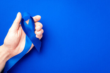 Prostate awareness. Blue ribbon in hands isolated on deep blue background. Awareness prostate...