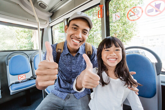 asian father taking his daughter to school by bus thumb up