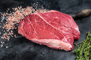 Prime Beef raw steak piece on a butchery knife. Black background. Top view