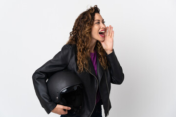 Young caucasian woman holding a motorcycle helmet shouting with mouth wide open to the side
