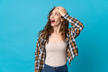 Young caucasian woman isolated on blue background doing surprise gesture while looking to the side