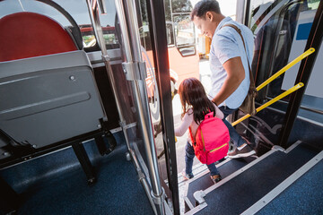 asian father taking his daughter to school by riding bus public transport © Odua Images