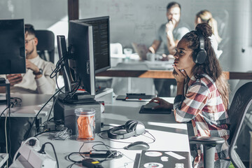 Young female programmer sitting at the desk in her office and working .	