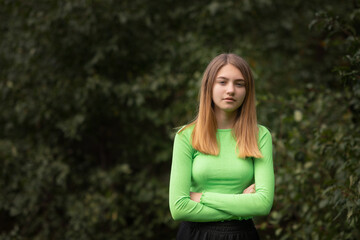 Obraz premium Portrait of a young beautiful blonde girl in a yellow-green blouse in the park.