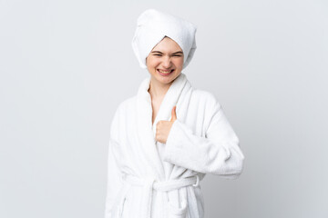 Teenager girl in a bathrobe isolated on white background with thumbs up because something good has happened