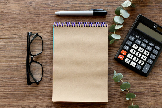 craft bloknot with place for text on wood background with calculator