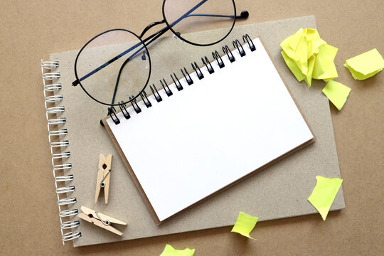 Gray Notepad With White Coiled Spring On A Background Of Beige Crumpled Craft Paper. With Empty Space For Text And Design