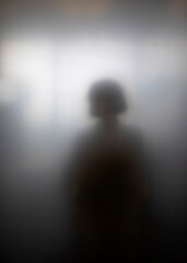 Sihouette of girl highly diffused by frosted glass