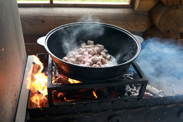 Cooking meat in cauldron on fire
