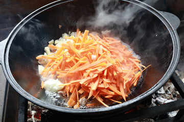Cooking zirvak in cauldron on fire