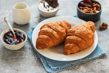 Two French croissants on a plate, nuts, jam and chocolate.French breakfast. Cozy morning.