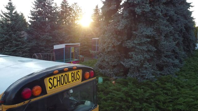 School bus parked at entrance of public school building. Aerial drone overhead shot.