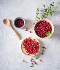 juicy forest lingonberry with handmade jam  in a wooden bowl on white table. Concept homemade healthy food. Top view and copy space