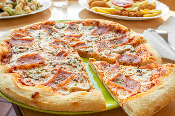 Portion of ham and mushroom pizza with oregano separated from the pizza