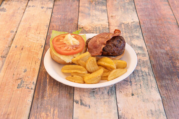 Delicious unclosed beef burger with smoked bacon, tomato slices, mayonnaise and lettuce garnished with fried potato wedges