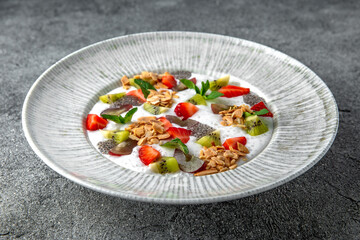 Healthy vegetarian wholesome breakfast porridge with berries, fruits and chia seeds. Ready menu for the restaurant. Neutral gray blue textured background