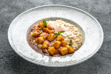 Oatmeal in milk with caramelized peach. Ready menu for the restaurant. Neutral gray blue textured background