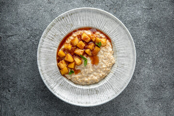 Oatmeal in milk with caramelized peach. Ready menu for the restaurant. Neutral gray blue textured background
