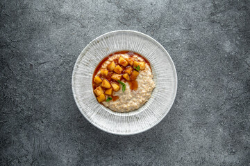 Oatmeal in milk with caramelized peach. Ready menu for the restaurant. Neutral gray blue textured background